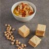 A bowl of hummus lying next to some biscuits and legumes.